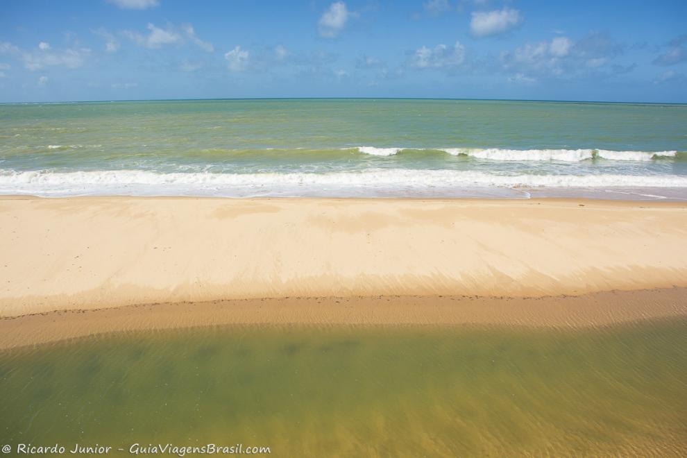 Imagem das águas cristalinas da piscina natural da Praia Japara Grande e do mar.